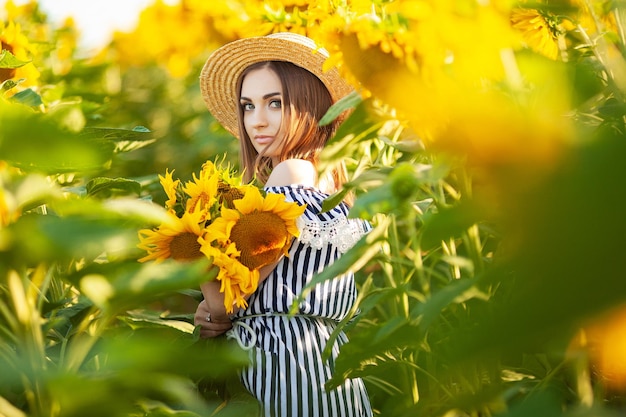 Beautiful young woman in sunflower field on summer day