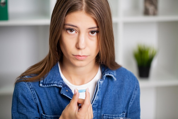 Beautiful young woman taking pill at home