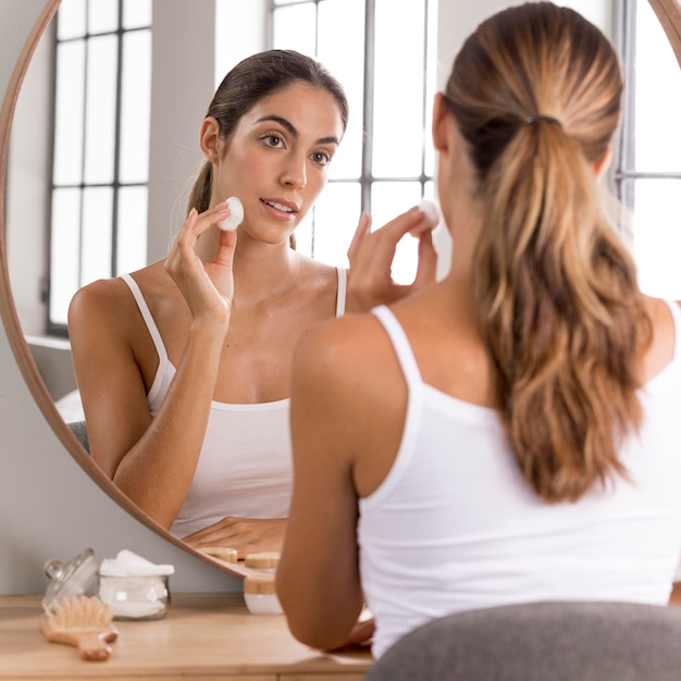 Beautiful young woman using day cream at home