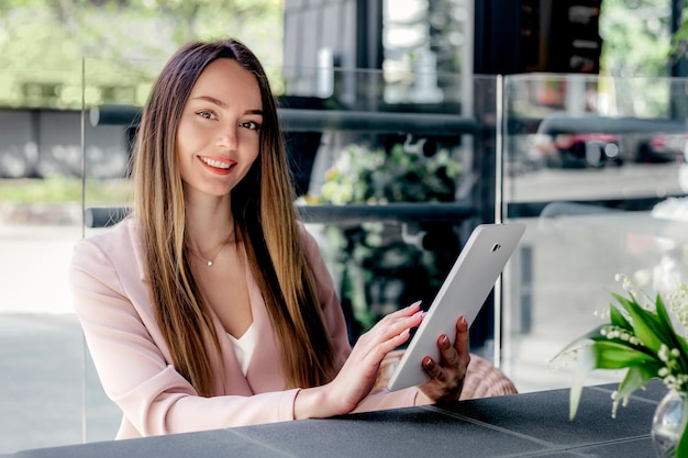 Beautiful young woman using digital tablet at cafe