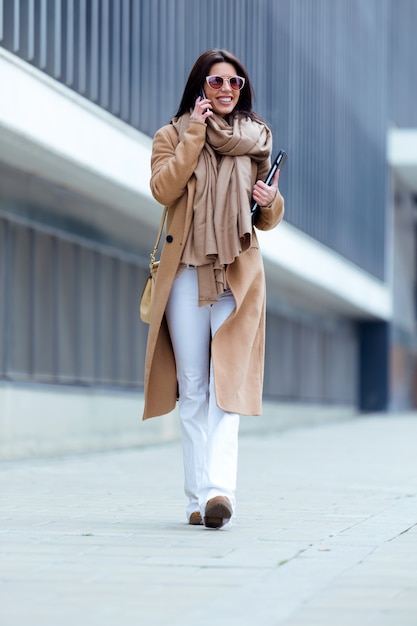 Beautiful young woman using her mobile phone in the street.