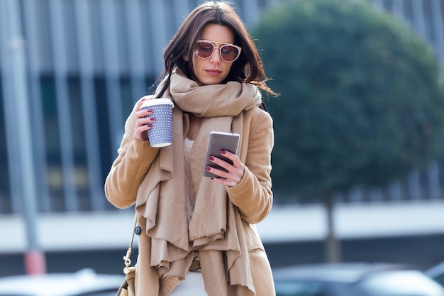 Beautiful young woman using her mobile phone in the street.