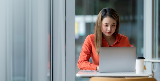 Beautiful young woman using laptop sitting on a coffee shop