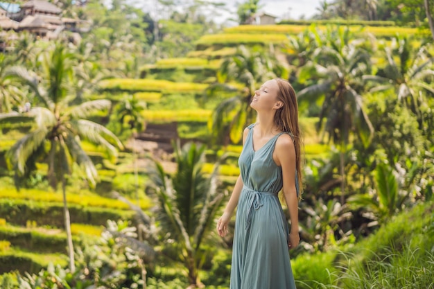 Beautiful young woman walk at typical Asian hillside with rice farming mountain shape green cascade rice field terraces paddies Ubud Bali Indonesia Bali travel concept