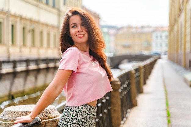 a beautiful young woman walks through city center along canals on a summer day in saint petersburg