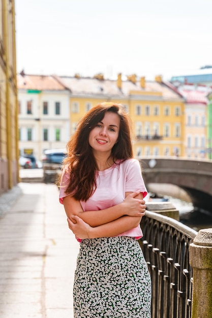 a beautiful young woman walks through city center along canals on a summer day in saint petersburg