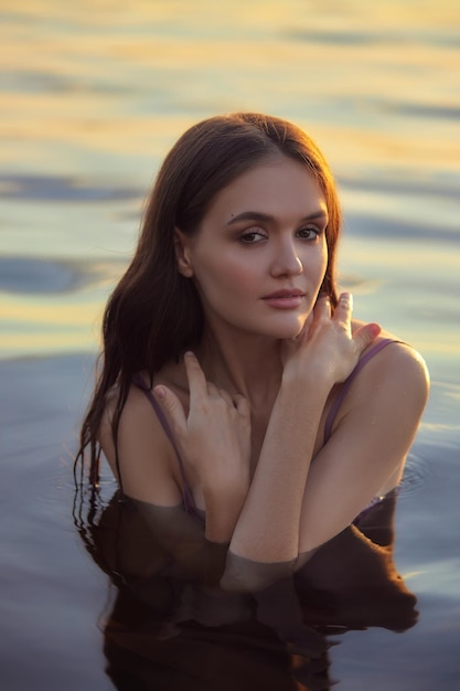 Beautiful young woman in the water at sunset Natural beauty long hair woman in the lake