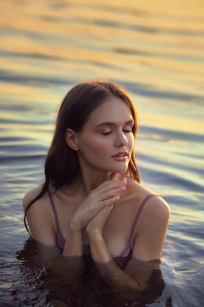 Beautiful young woman in the water at sunset Natural beauty long hair woman in the lake