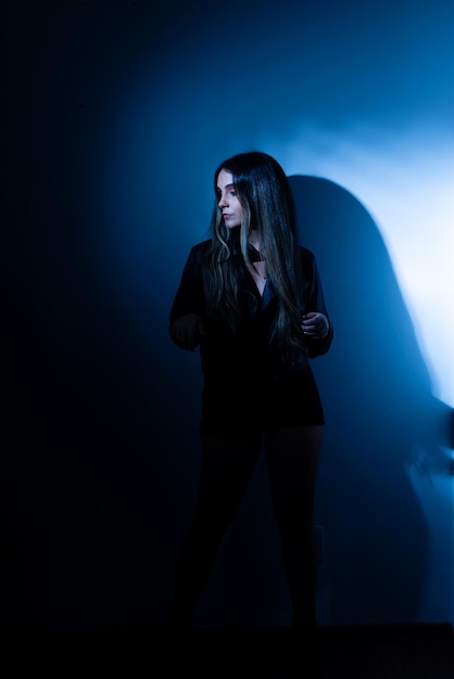 Beautiful young woman wearing black clothes leaning against a wall with blue and white color