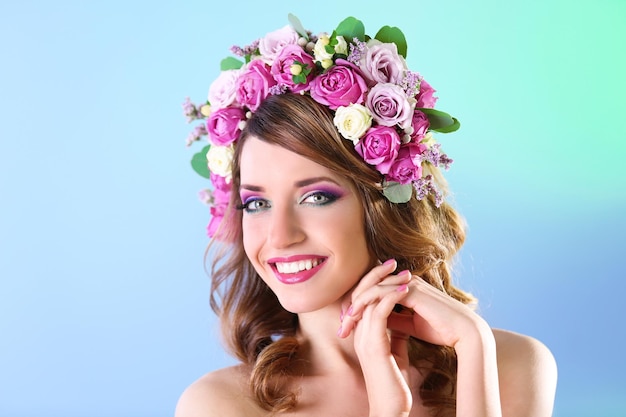 Beautiful young woman wearing floral headband on a blue background