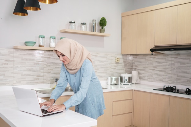 Beautiful young woman wearing hijab drinking a cup of coffee whi