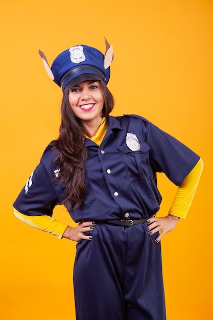 Photo beautiful young woman wearing police costume over yellow background. having fun.