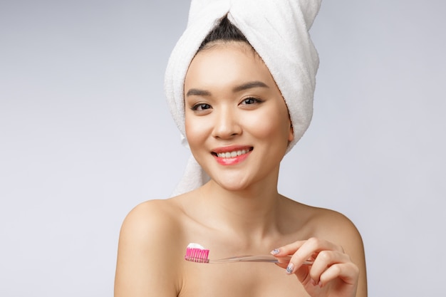 Beautiful young woman on white isolated background holds a toothbrush, Asian