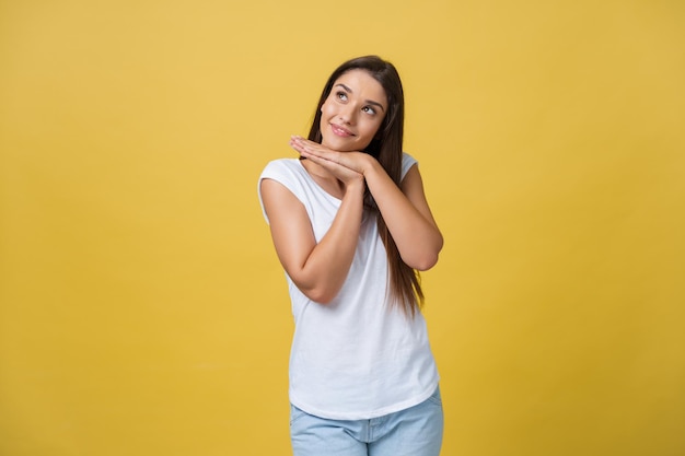 Beautiful young woman in white shirt is holding head in hands smiling and looking at camera