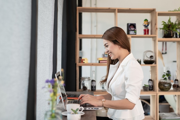 Beautiful young woman who is an Asian businessman smiling happy working with a laptop 