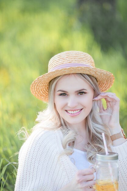 Beautiful young woman in a wicker hat is resting on a picnic in a blooming garden. White flowers. Spring. Happiness.