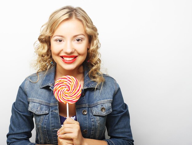 Beautiful young woman with big colorful lollipop