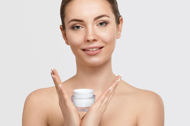 Beautiful young woman with clean fresh skin Girl holding cream in her hand Spa and face care