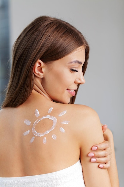 Beautiful young woman with cream on her shoulder.