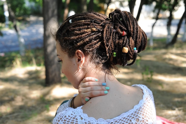 Beautiful young woman with dreadlocks hairstyle gathered in a ponytail decorated assorted beads