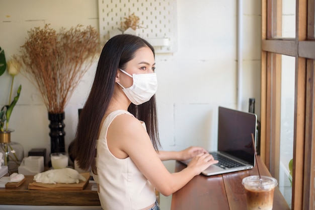 Beautiful young Woman with face mask is sitting in coffee shop