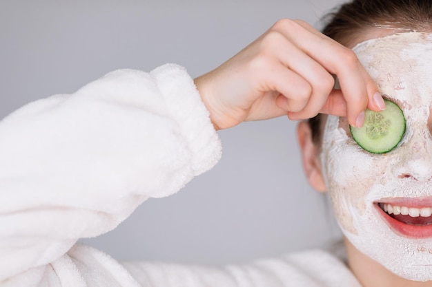 Beautiful young woman with facial mask on her face holding slice