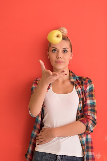 Photo beautiful  young woman with hair bun plays with apple over color background with copyspace expressing different emotions