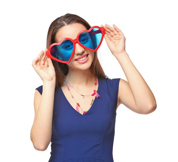 Beautiful young woman with heartshaped glasses on white background