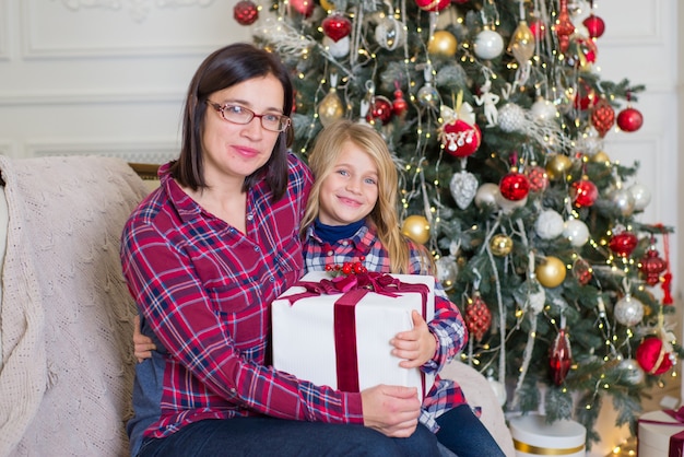 beautiful young woman with little daughter near the christmas tree at christmas at home