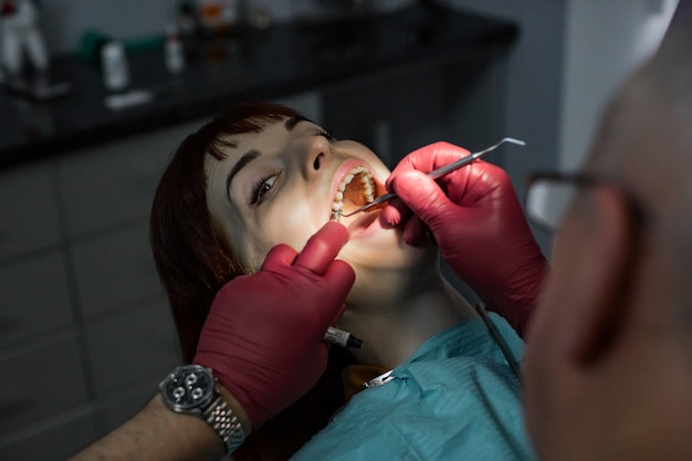 Beautiful young woman with open mouth at dentist having dental treatment at dentist's office.