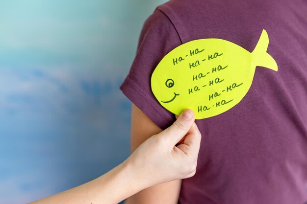 Photo beautiful young woman with paper stickers attached to her friends back april fools day celebration