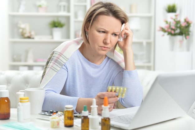 Photo beautiful young woman with pills using laptop