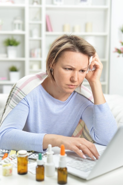 Photo beautiful young woman with pills using laptop