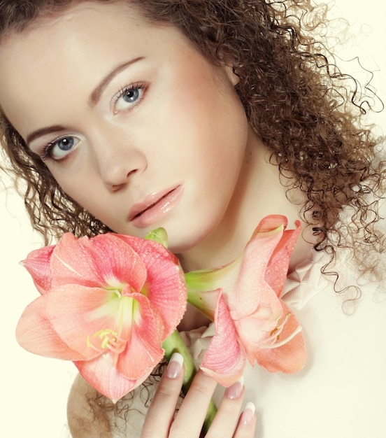 Beautiful young woman with pink flower over white background