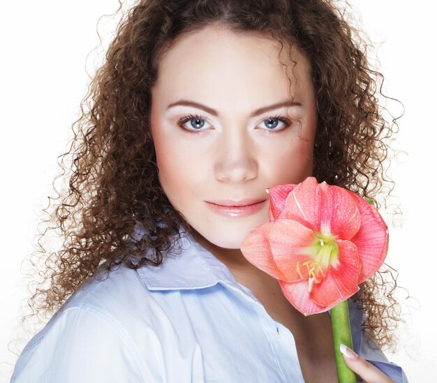 Beautiful young woman with pink flower over white background