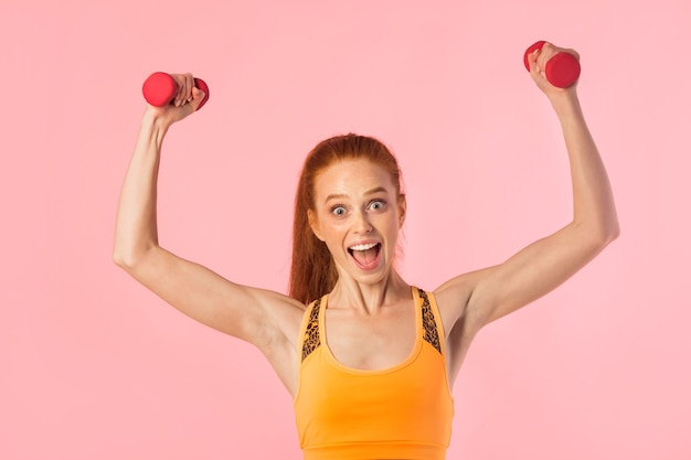 beautiful young woman with red hair with dumbbells in hands