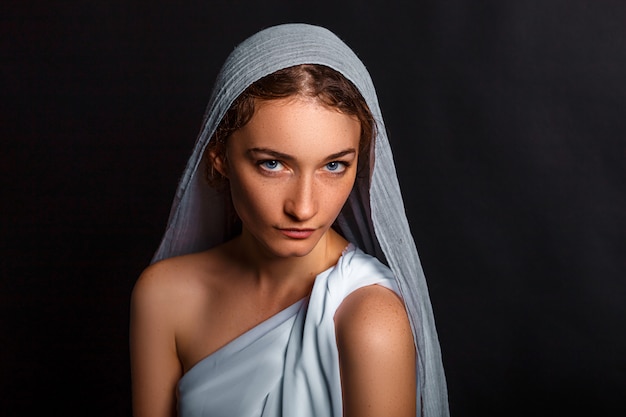 Beautiful young woman with a scarf on her head, and a rosary in her hands, humble look, believing woman.