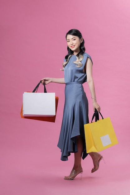 Beautiful young woman with shopping bags on color background