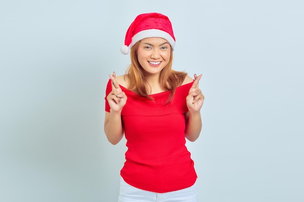 Beautiful young woman with short hair wearing christmas hat smilng and gesturing finger crossed