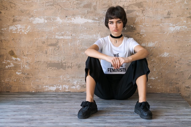 Beautiful young woman with short haircut on background wall Posing in white