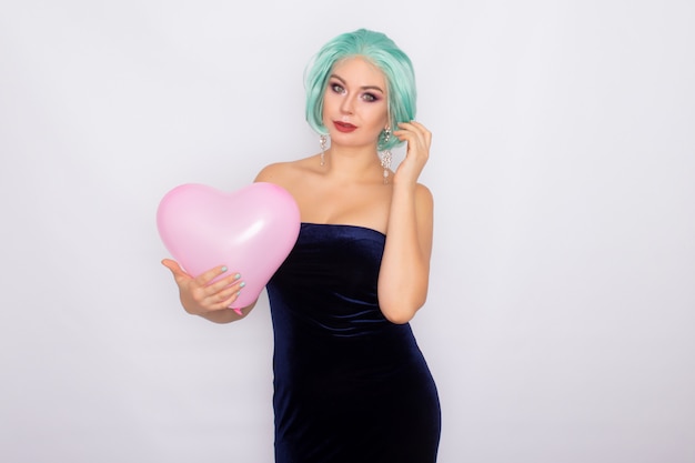 Beautiful young woman with short mint hair standing holding heart balloon