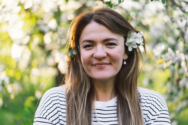 Beautiful young woman with spring flowers enjoying nature and laughing on spring garden