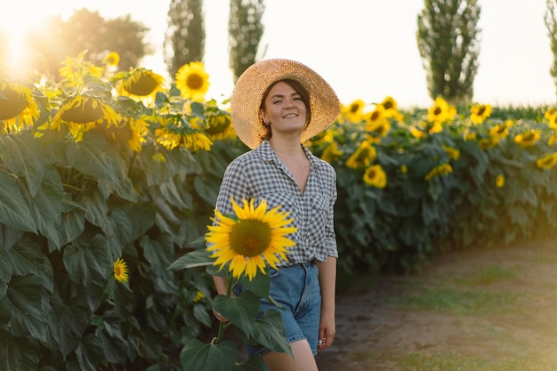 Beautiful young woman with sunflowers enjoying nature and laughing on summer sunflower field