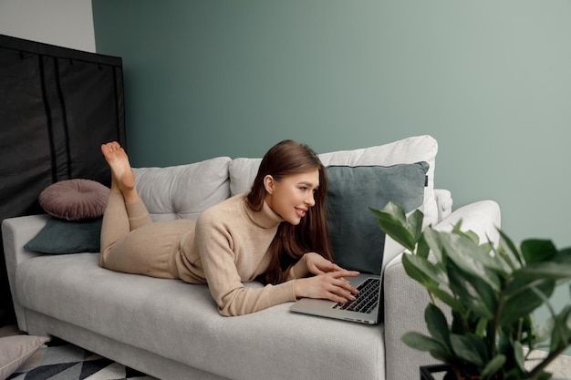 Beautiful young woman working with laptop on couch nline shoping PaymentBusinesswoman using laptop