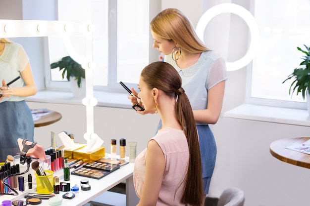  Beautiful young women looking into the mirror while being in the beauty salon