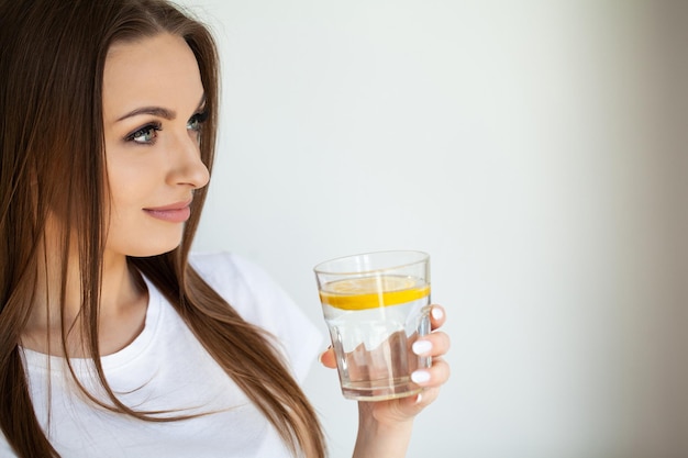 Beautiful youthful lady refreshing herself with lemon water