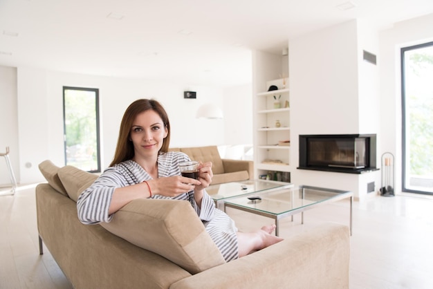 Beautifull young woman in a bathrobe enjoying morning coffee in her luxurious home villa