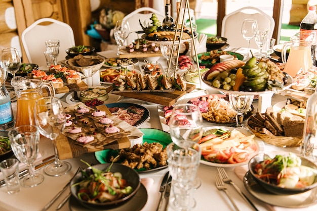 Beautifully decorated catering banquet table with different food snacks and appetizers with sandwich caviar fresh fruits on corporate party event or wedding celebration