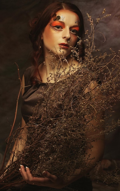 Beauty and art concept Young woman with bright make up with dry branches