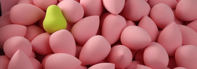 Beauty background a bunch of pink gentle sponges and one contrast green conflict for makeup banner